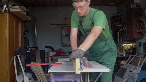 Carpenter in protective gloves and glases handles a wooden board works on planin Stock Footage 169155011