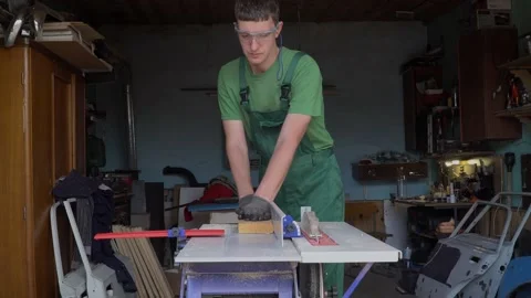 Carpenter in protective gloves and glasses plans a wooden blank on a woodworking Video stock 169330917