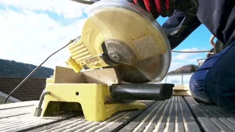 Carpenter in protective gloves precisely cuts off 6x2 wooden beam for a roof Stock Footage 149944623