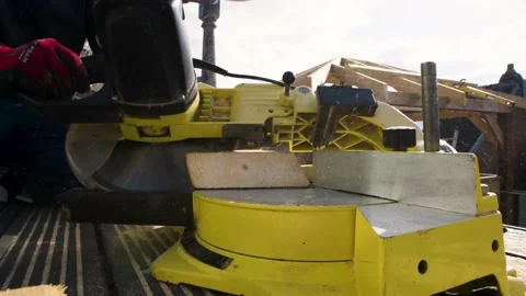 Carpenter in protective gloves precisely cuts off 6x2 wooden beam for a roof Video stock 149944633