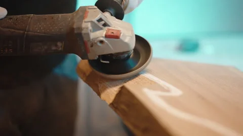 Carpenter in protective uniform using angle grinder for sharpening wood in Stock Footage 262961425