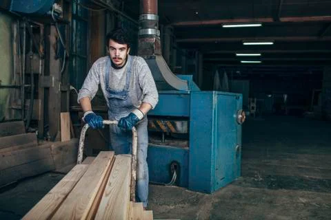 Carpenter pushing stack of wood planks on cart at workshop Foto stock