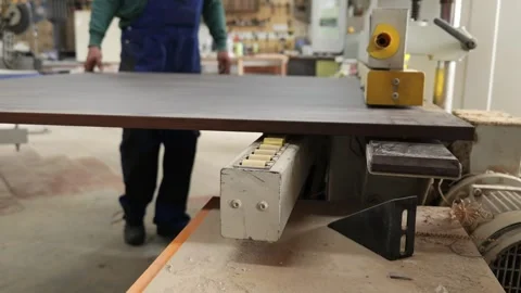 Carpenter pushing wooden panel into edge banding machine Stock Footage 335464096