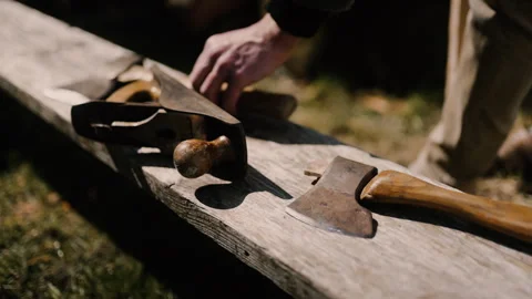 Carpenter put's down and picks up carving axe tools, in garden sunlight Stock Footage 271190408