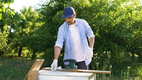 Carpenter puts on protective glasses and sands wooden plank with electric tool Stock Footage 112889713