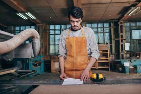 Carpenter reading document on bench in workshop Stock Photos