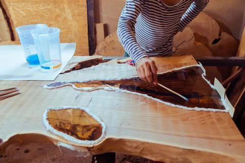 Carpenter removing air bubbles from epoxy table Stock Photos
