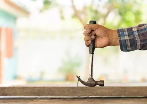 The carpenter removing rust nail from old wood to diy table. Stock Photos