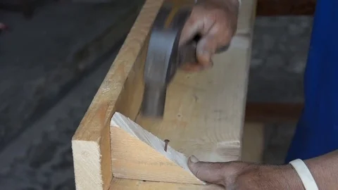 Carpenter' s hands hitting a nail on the head with old and used wood Stock Footage 83792286
