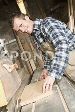 A carpenter sawing wood in a workshop Stock Photos