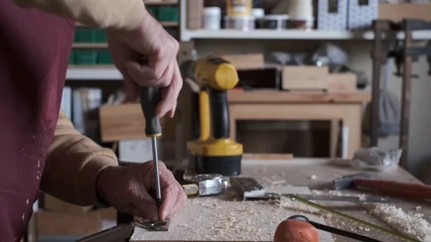 Carpenter screwing a hinge to a board with a screwdriver Stock Footage 123121021