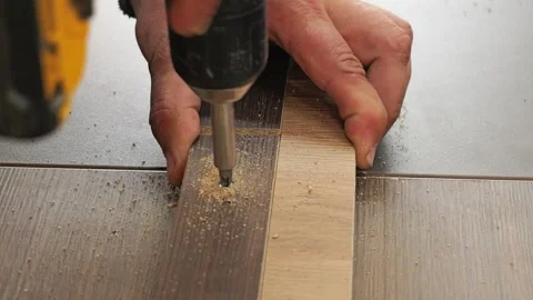 Carpenter screwing a wood laminate threshold strip 库存影片 335462178