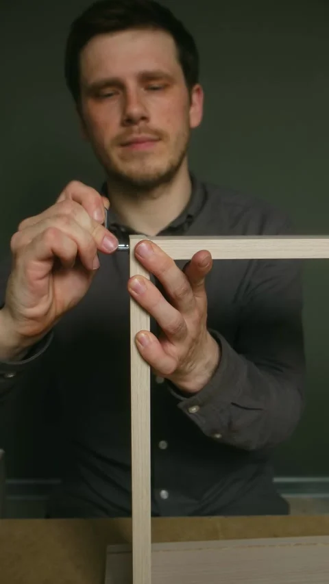 Carpenter securing corner bracket on wooden frame Stock Footage 311944206