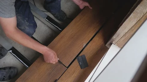 Carpenter sets spacing of deck boards on floor wood panel. Flooring installation Stock Footage 155659850