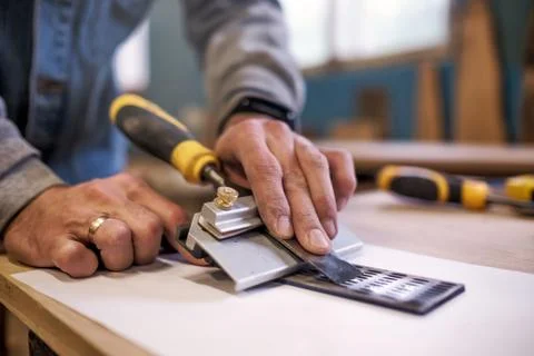 Carpenter sharpening a chisel close up view Stock Photos