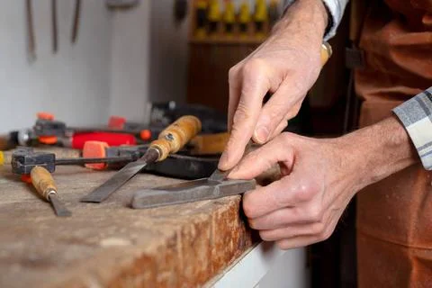Carpenter sharpening a chisel. woodworking process with hand tools in a ca... Stock Photos