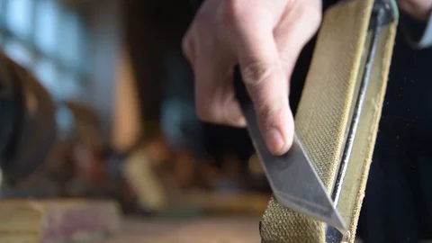 The carpenter sharpens the knife manually. Slow-motion close-up Video stock 128408870