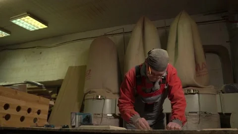 Carpenter stands behind the workplace, polishes with sandpaper, processes wood Stock Footage 149123162