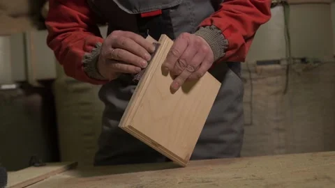 Carpenter stands behind the workplace, polishes with sandpaper, processes wood Stock Footage 149123896