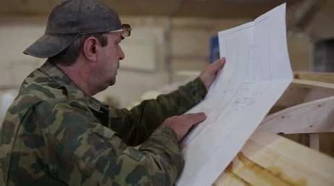 Carpenter studies the draft of the boat at the shipyard Stock Footage 59782636