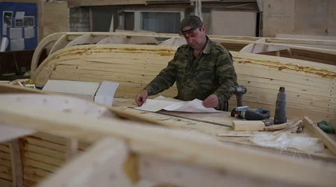 Carpenter studies the draft of the boat at the shipyard Stock Footage 59782856
