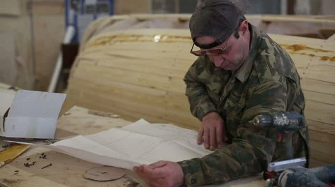 Carpenter studies the draft of the boat at the shipyard Stock Footage 59782908