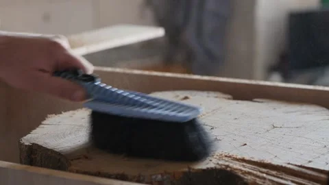 A carpenter sweeps chips off an acacia tree stump with a brush. woodworking Stock Footage 147404368