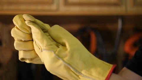 Carpenter taking off yellow gloves at work. Pulls it away, remove from Hands.  库存影片 129459533