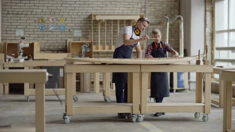 Carpenter teaching son how to make wooden boat Stock Footage 142169809