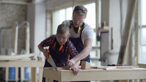 Carpenter teaching son how to use hand saw Stock Footage 142171509