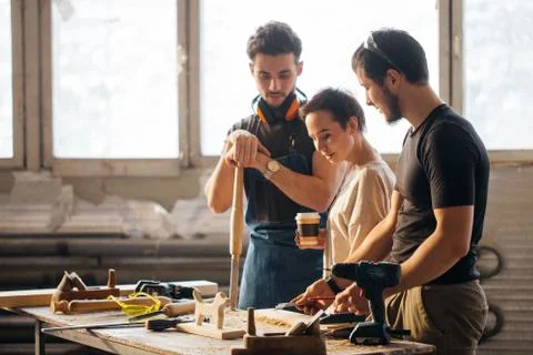 Carpenter Training Female Apprentice To Use Plane 库存照片