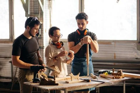 Carpenter Training Female Apprentice To Use Plane 库存照片