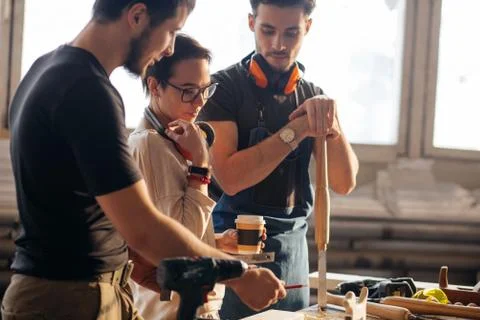 Carpenter Training Female Apprentice To Use Plane 库存照片