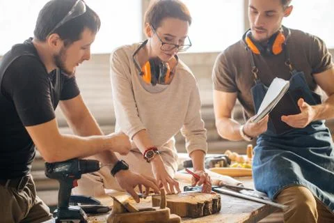 Carpenter Training Female Apprentice To Use Plane Stock Photos