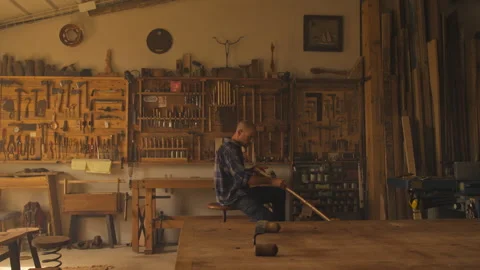 Carpenter trimming wood piece while sitting in woodwork workshop Stock Footage 275631605