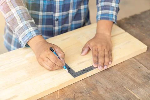 The carpenter use solid square to measure wood sheet. Stock Photos
