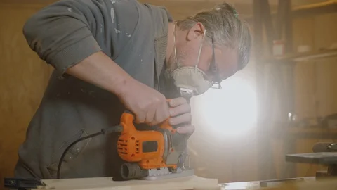 Carpenter uses electric jigsaw to cut wooden board, wood craftsman working Stock Footage 128750185