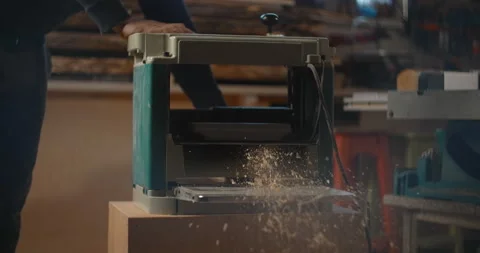 Carpenter uses electric planing machine at his woodworking workshop, timber Stock Footage 149666404
