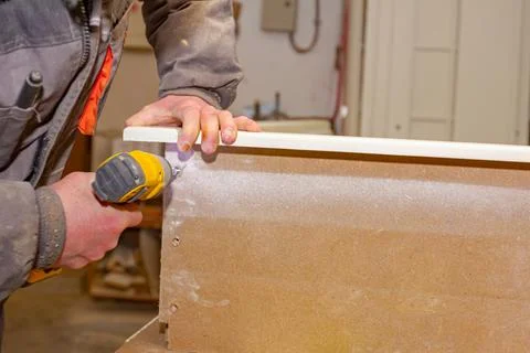 Carpenter uses hand drill, acu power tool and tightens the screws on the wood Stock Photos