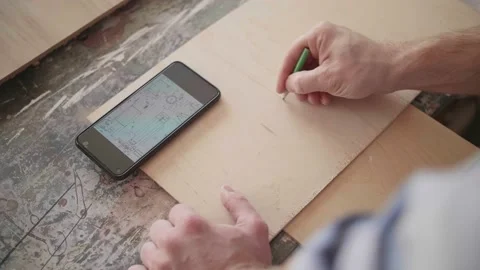 Carpenter uses mobile phone for drawing details Stock-Footage 153495649