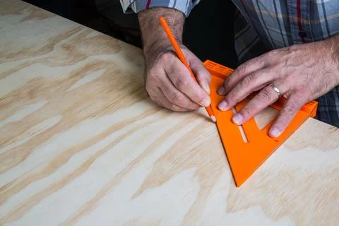 Carpenter Using 45 degree Triangle to Do Layout on Wooden Sheet Foto stock