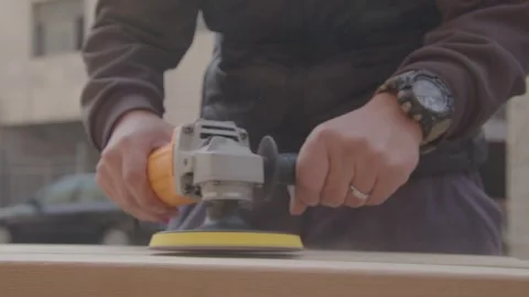 Carpenter Using Angle Grinder on Wood Plank Outdoors, Close-up Shot Stockbeeldmateriaal 336561528