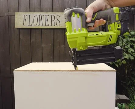 Carpenter using a battery driven nail gun assembling wooden flower container Stock Photos