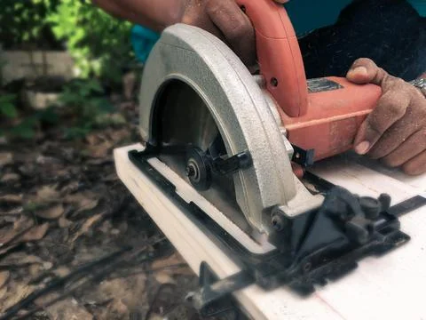 Carpenter is using a chainsaw to saw pieces of wood for use in building Stock Photos