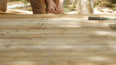 Carpenter using chalk line to take measurement on wooden deck in 4k Stock Footage 126727651