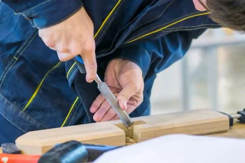Carpenter using chisel to carve wood on rough workbench at workshop Stock Photos