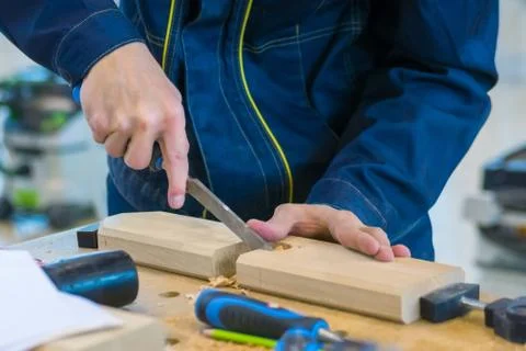 Carpenter using chisel to carve wood on rough workbench at workshop Stock Photos