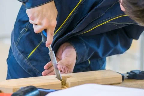 Carpenter using chisel to carve wood on rough workbench at workshop Stock Photos