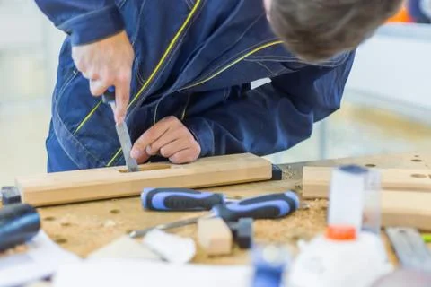 Carpenter using chisel to carve wood on rough workbench at workshop Stock Photos