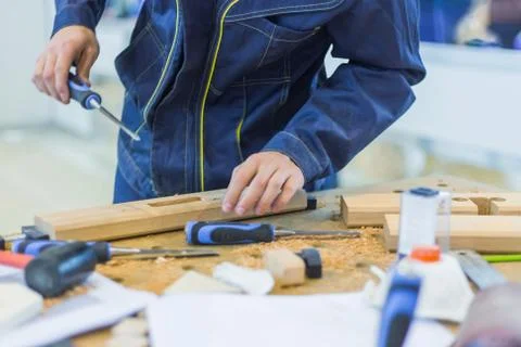 Carpenter using chisel to carve wood on rough workbench at workshop Stock Photos